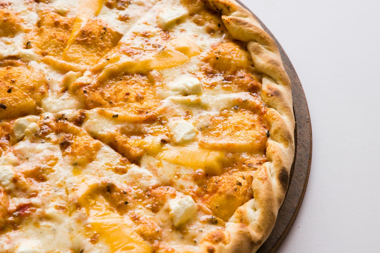 Pizza med mycket ost serverad på träbricka